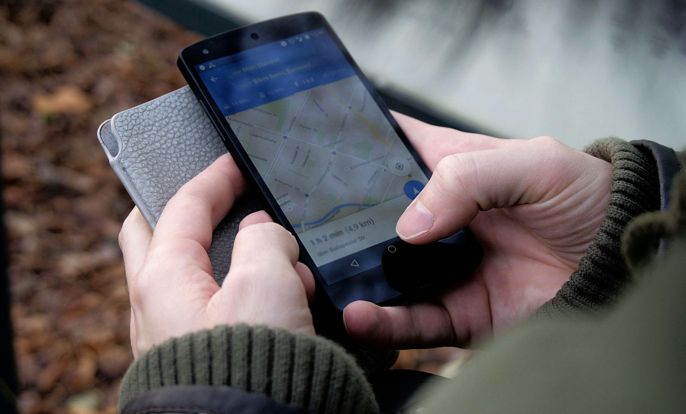 Hands holding a phone with Google Maps open on the screen